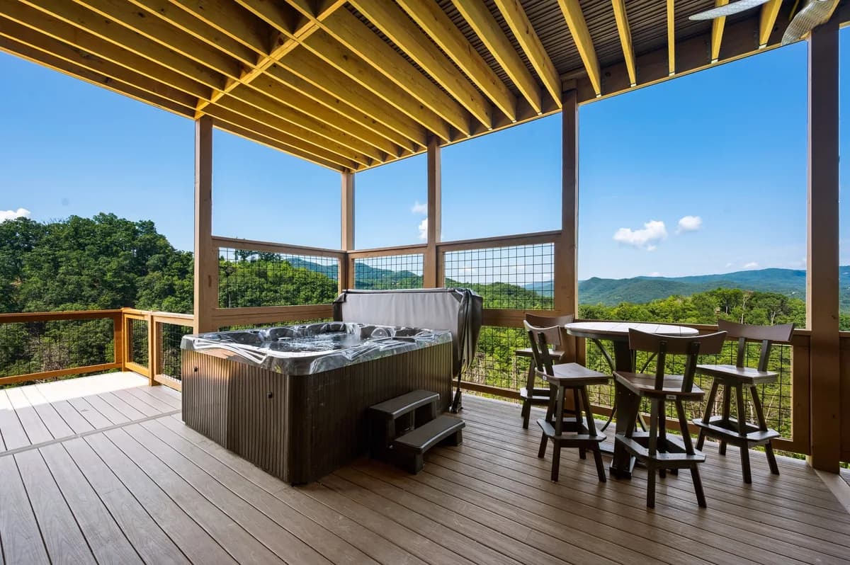 A covered mountain-view deck with a hot tub, spotless and guest-ready