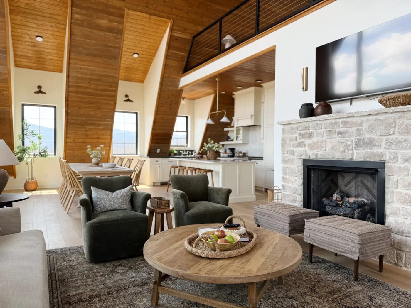 A bright, freshly cleaned A-frame great room with vaulted wood ceilings and a stone fireplace, guest-ready
